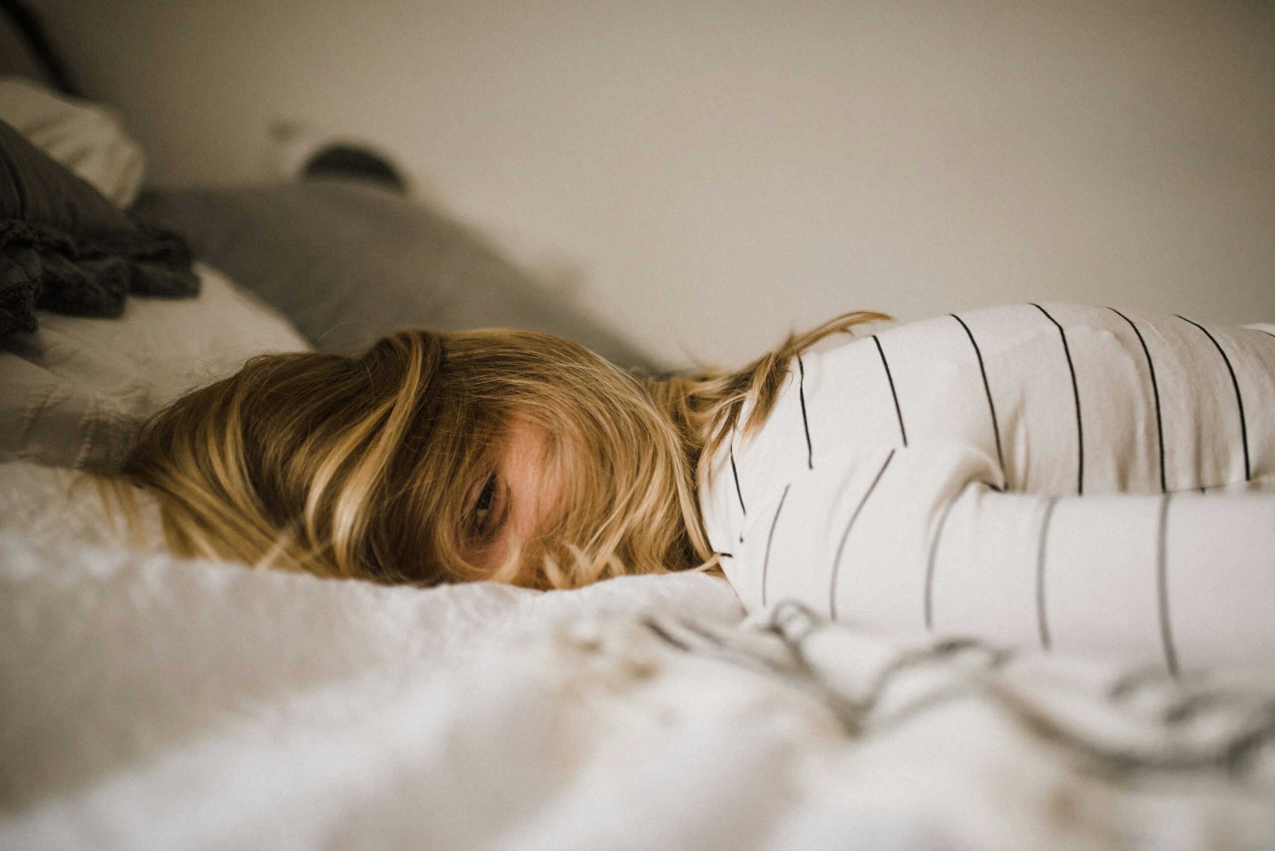 Woman laying face down on the bed stressed out from work.